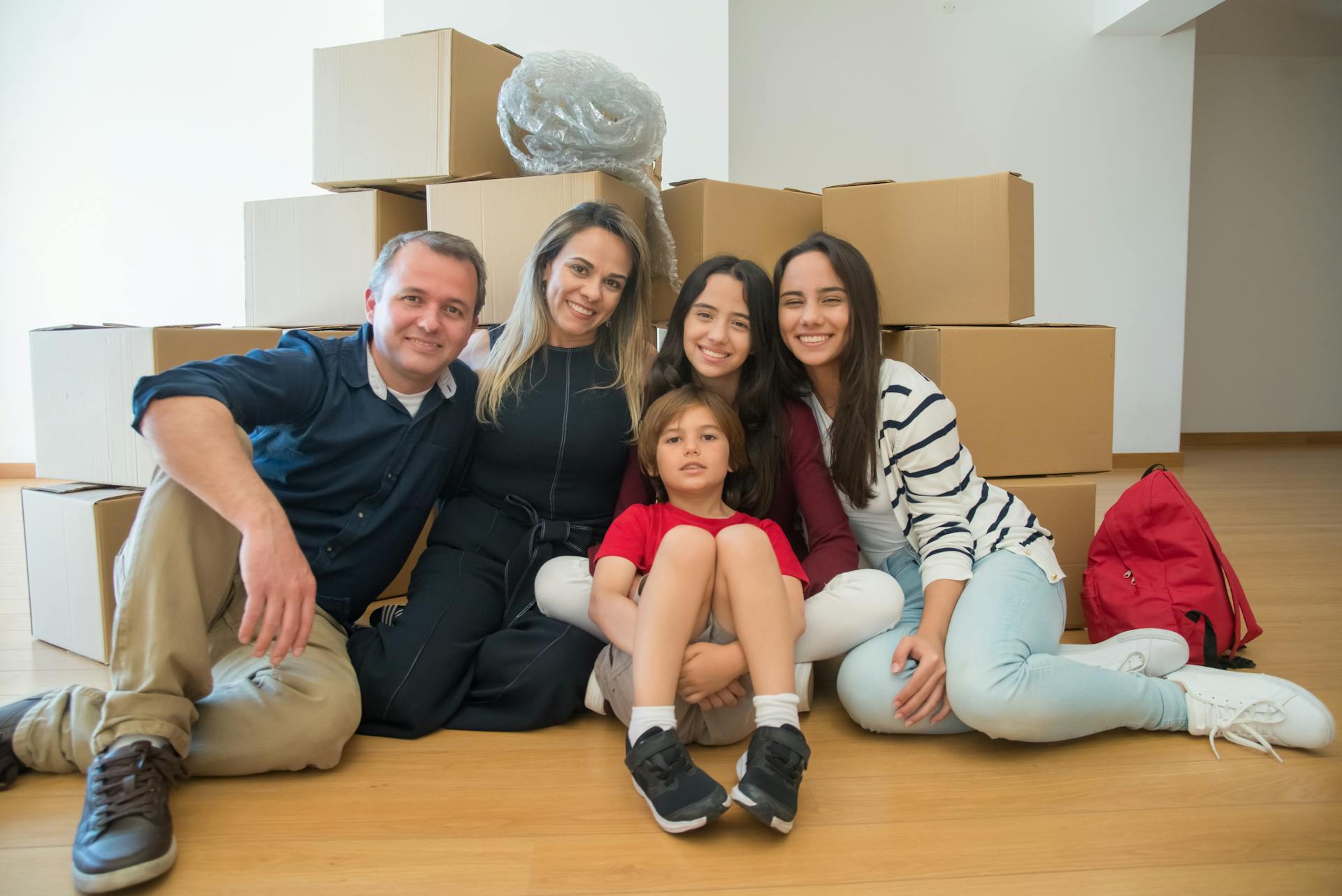 Happy family of five in new home with boxes behind them